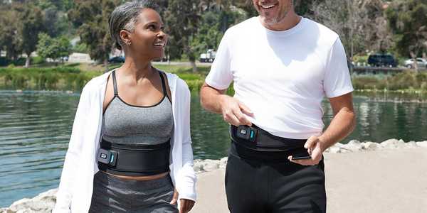 A man and a woman walking outdoors wearing a smart toning belt.